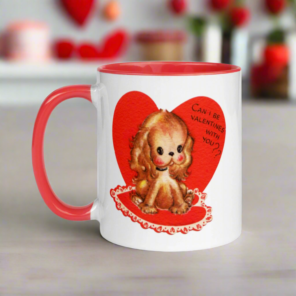 This ceramic glossy coffee cup features a vintage midcentury Valentine's Day illustration of a golden puppy sitting on a heart rug. There is a heart behind her that says Can I be Valentines with you?