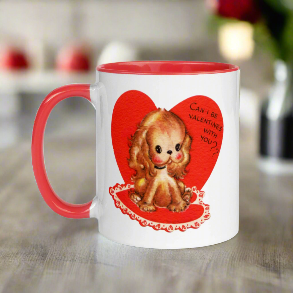 This ceramic glossy coffee cup features a vintage midcentury Valentine's Day illustration of a golden puppy sitting on a heart rug. There is a heart behind her that says Can I be Valentines with you?