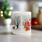 This ceramic glossy coffee mug features a vintage Christmas illustration of a snowy winter scene in the country. There is a red barn and a horse pulling a red sleigh with a Christmas tree.