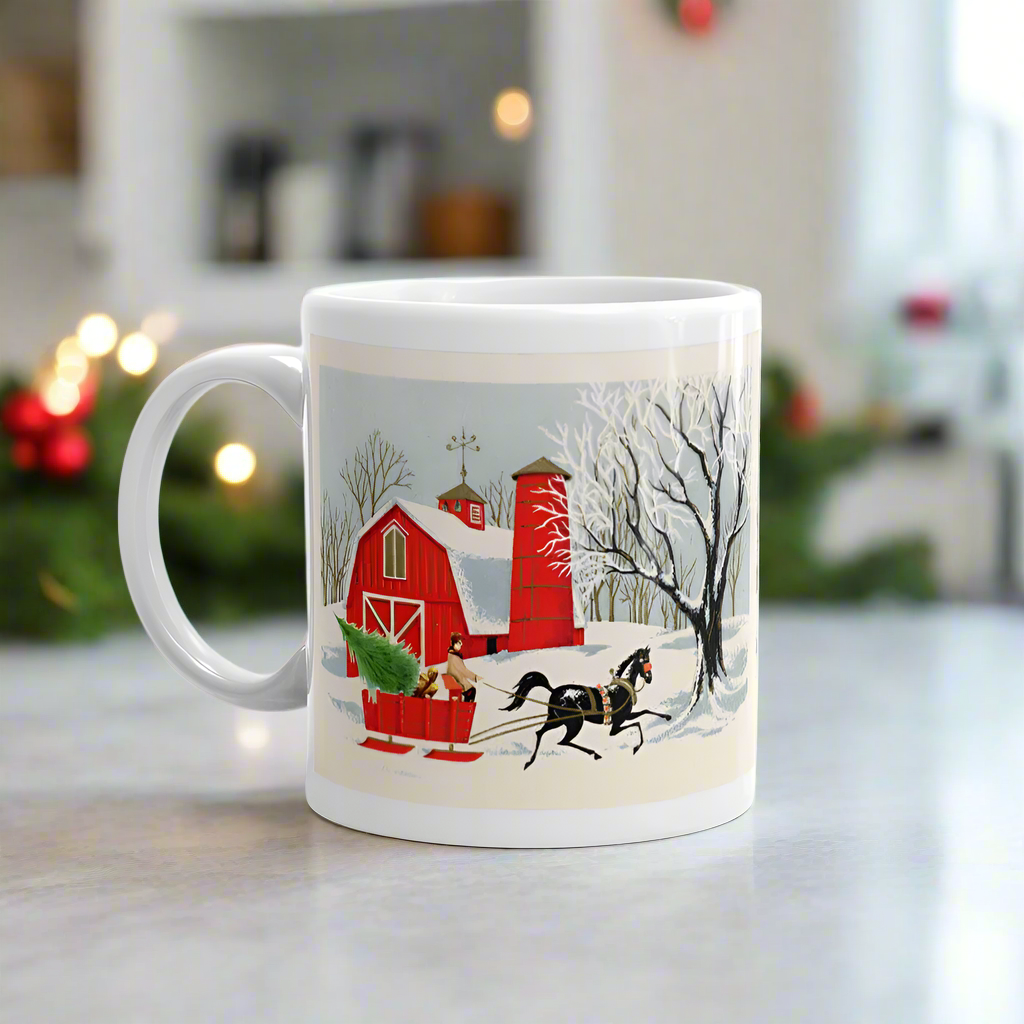 This ceramic glossy coffee mug features a vintage Christmas illustration of a snowy winter scene in the country. There is a red barn and a horse pulling a red sleigh with a Christmas tree.