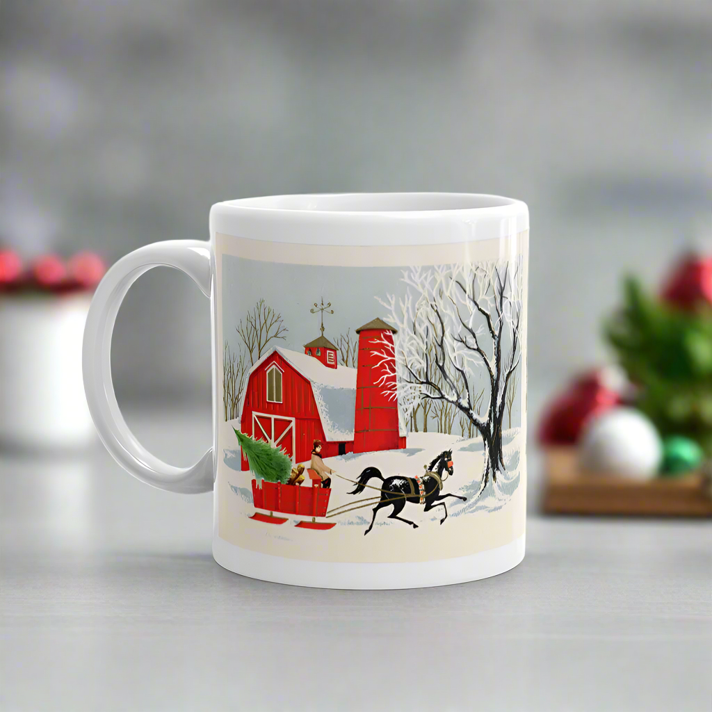 This ceramic glossy coffee mug features a vintage Christmas illustration of a snowy winter scene in the country. There is a red barn and a horse pulling a red sleigh with a Christmas tree.