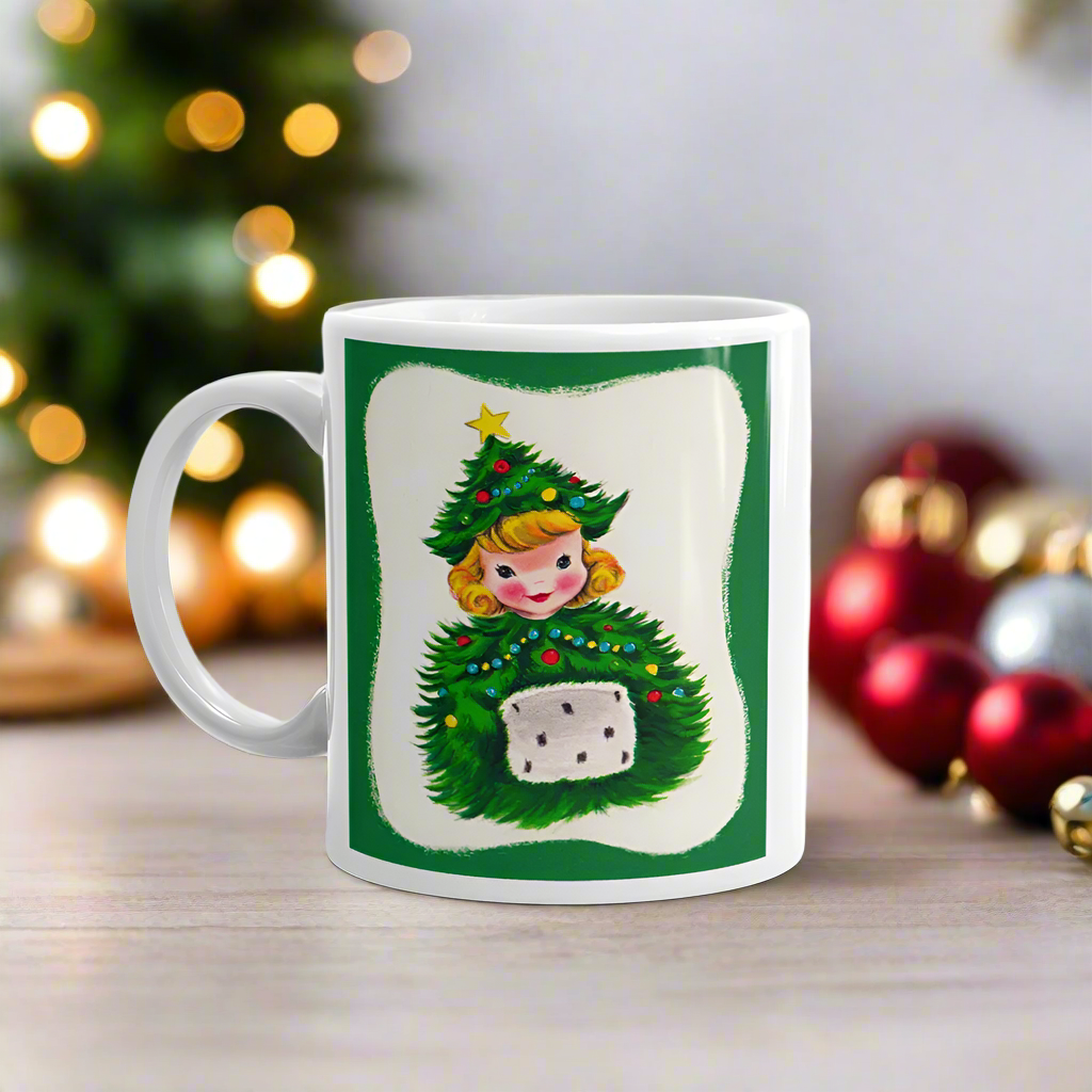 This ceramic glossy coffee mug features a blond girl wearing a christmas tree hat and coat. The hat is adorned with a yellow star on top. She is also wearing a white and green muff.