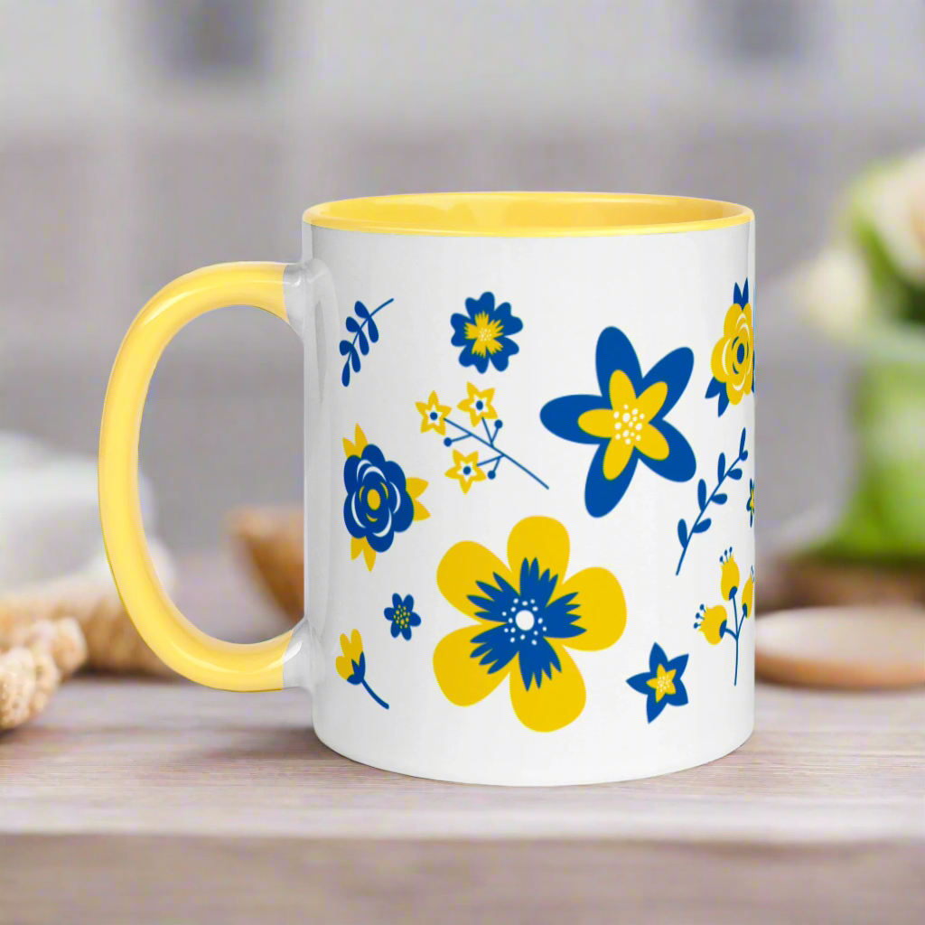 This ceramic glossy mug has a yellow handle and interior. The artwork features blue and yellow Ukranian country flowers.