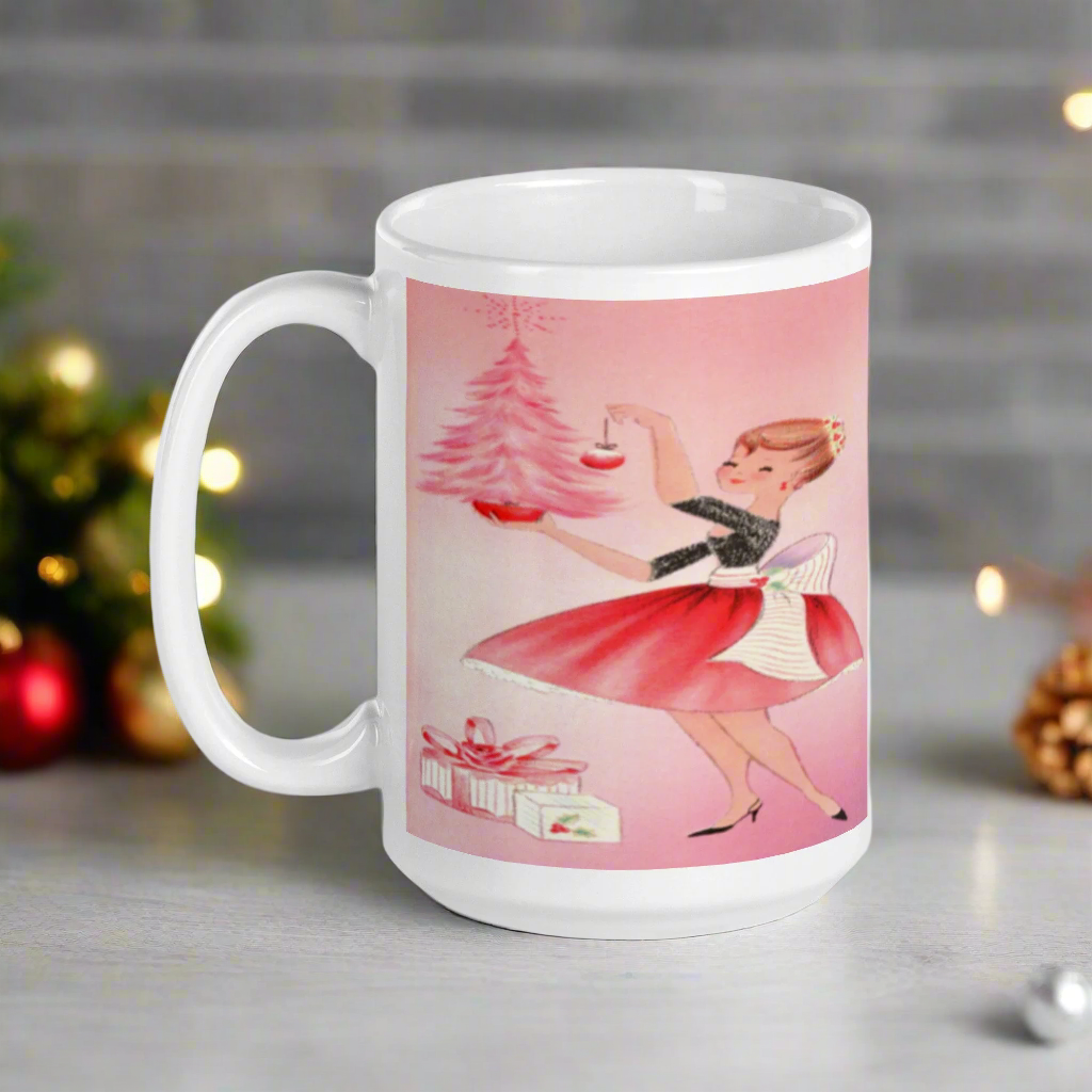 This glossy ceramic coffee mug features a midcentury retro Christmas illustration of a woman dressed in black and pink holding a small pink Christmas and ornament. There are a couple of presents and a pink background.