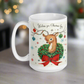 This ceramic glossy coffee mug is a midcentury christmas illustration that says Wishing you Christmas Joy. It features a reindeer with her tongue out wearing a Christmas wreath with a red bow. Her antlers are decorated with tinsel and  ornaments.