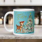 This glossy ceramic coffee mug features 
 Midcentury vintage artwork of an adorable reindeer with holly in her mouth, bunnies, and a Christmas Tree. There is gold lettering that says Season's Greetings and a blue felt background.