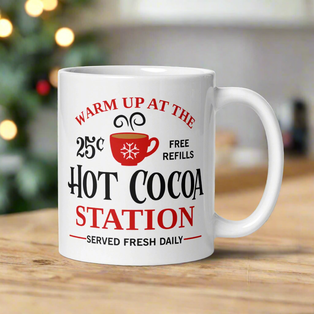 This ceramic glossy coffee mug says Warm Up At The Hot Cocoa Station Served Fresh Daily.It features a cute little red cup with a snowflake on it.