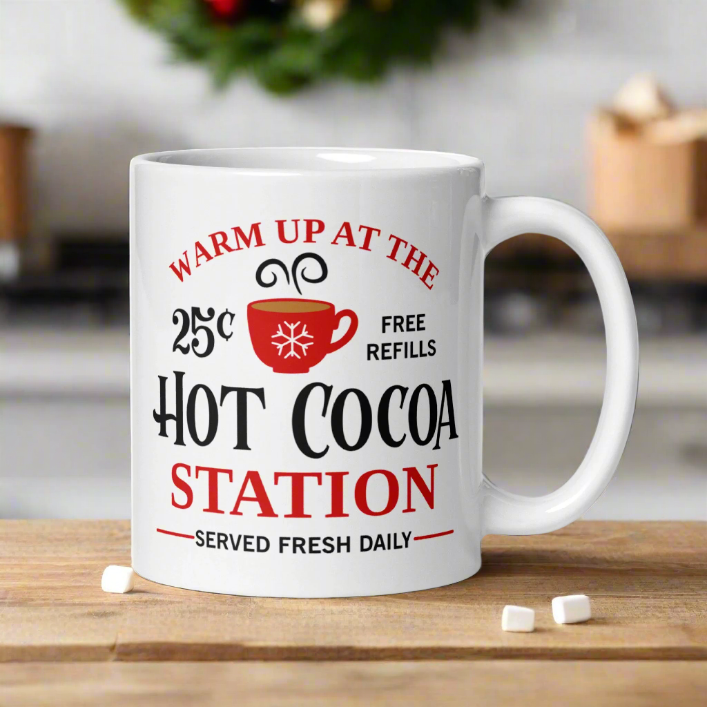 This ceramic glossy coffee mug says Warm Up At The Hot Cocoa Station Served Fresh Daily.It features a cute little red cup with a snowflake on it.