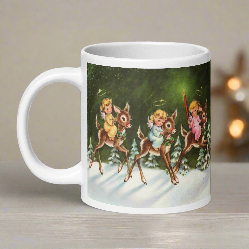 This ceramic glossy mug features three young angels riding reindeer in the snow.