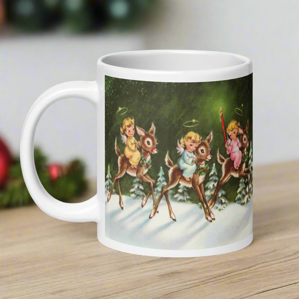 This ceramic glossy mug features three young angels riding reindeer in the snow.