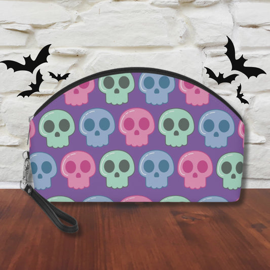 This purple cosmetic makeup bag features pastel green, blue and pink skulls. It has a black zipper and hook on wristlet strap.