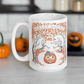 This glossy ceramic coffee mug features a retro vintage Halloween illustration that says Halloween with trees with spooky cute faces and orange leaves, with a jack o lantern in the middle and a black cat sleeping on the pumpkin.