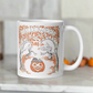 This glossy ceramic coffee mug features a retro vintage Halloween illustration that says Halloween with trees with spooky cute faces and orange leaves, with a jack o lantern in the middle and a black cat sleeping on the pumpkin.