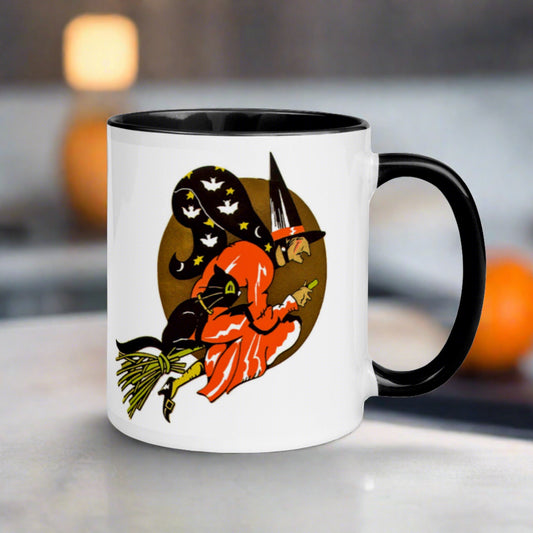 This Halloween mug features a vintage print of a witch flying on her broom with her black cat and a gold moon in the background. The witch's cape has bats and stars.