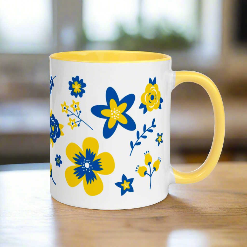 This ceramic glossy mug has a yellow handle and interior. The artwork features blue and yellow Ukranian country flowers.