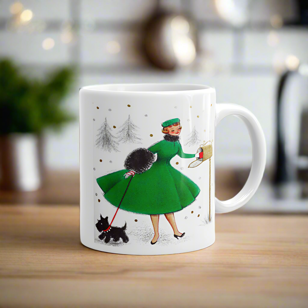 This ceramic glossy coffee mug features a midcentury retro Christmas illustration of a woman dressed in a green dress with a green hat, a black muff and red and white striped glove. She is walking her little black scottie and reaching into her mailbox. 