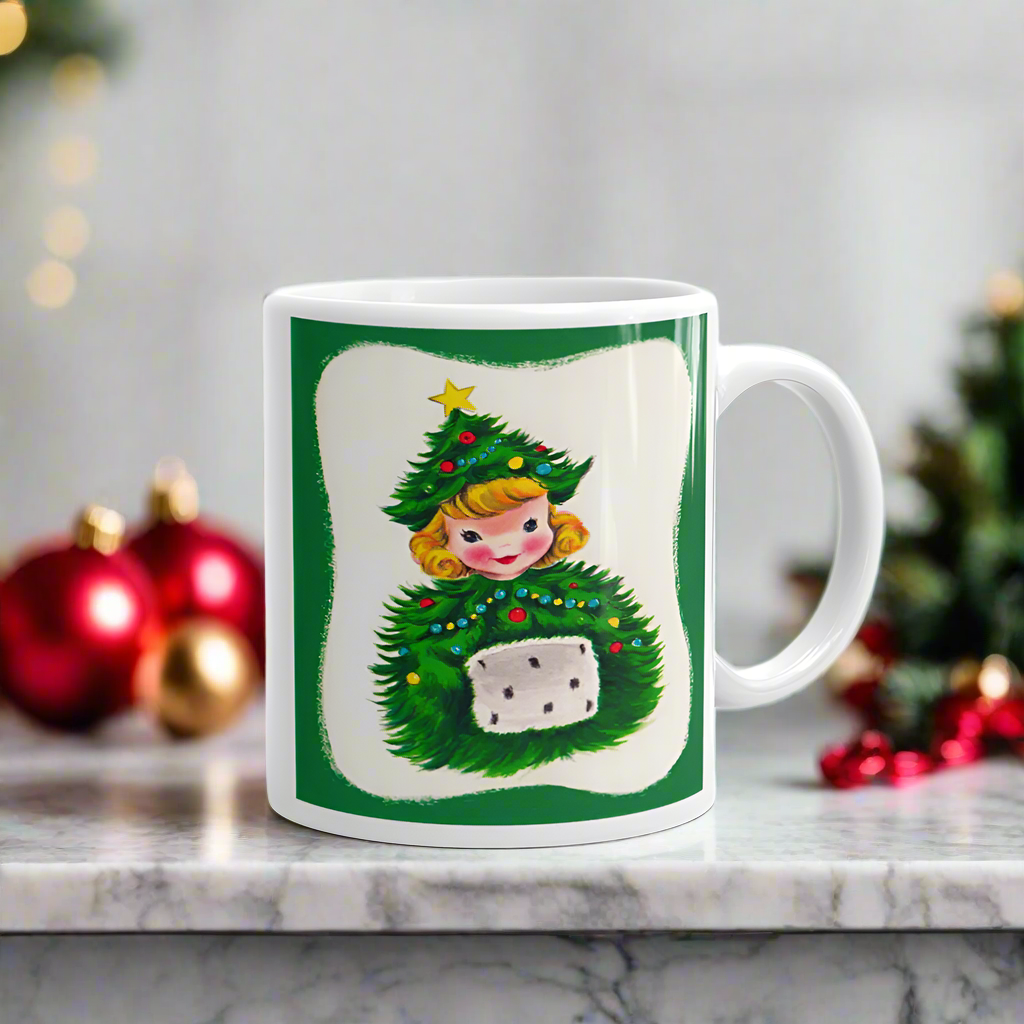 This ceramic glossy coffee mug features a blond girl wearing a christmas tree hat and coat. The hat is adorned with a yellow star on top. She is also wearing a white and green muff.