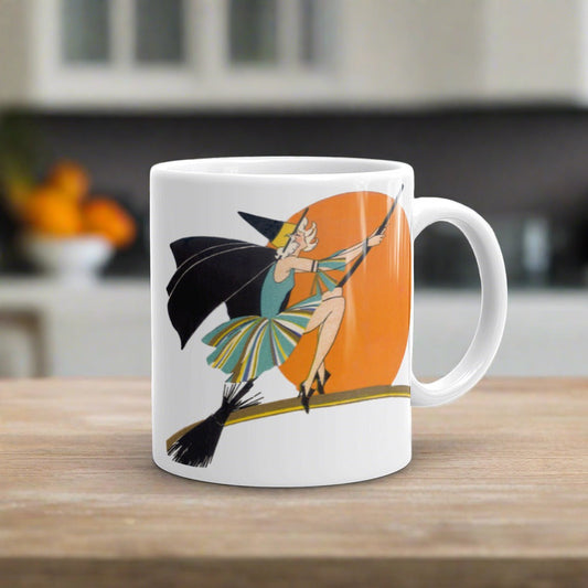 This ceramic coffee mug features a vintage deco illustration of a cute flapper witch flying on a broom with an orange full moon behind her. 