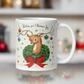 This ceramic glossy coffee mug is a midcentury christmas illustration that says Wishing you Christmas Joy. It features a reindeer with her tongue out wearing a Christmas wreath with a red bow. Her antlers are decorated with tinsel and  ornaments.