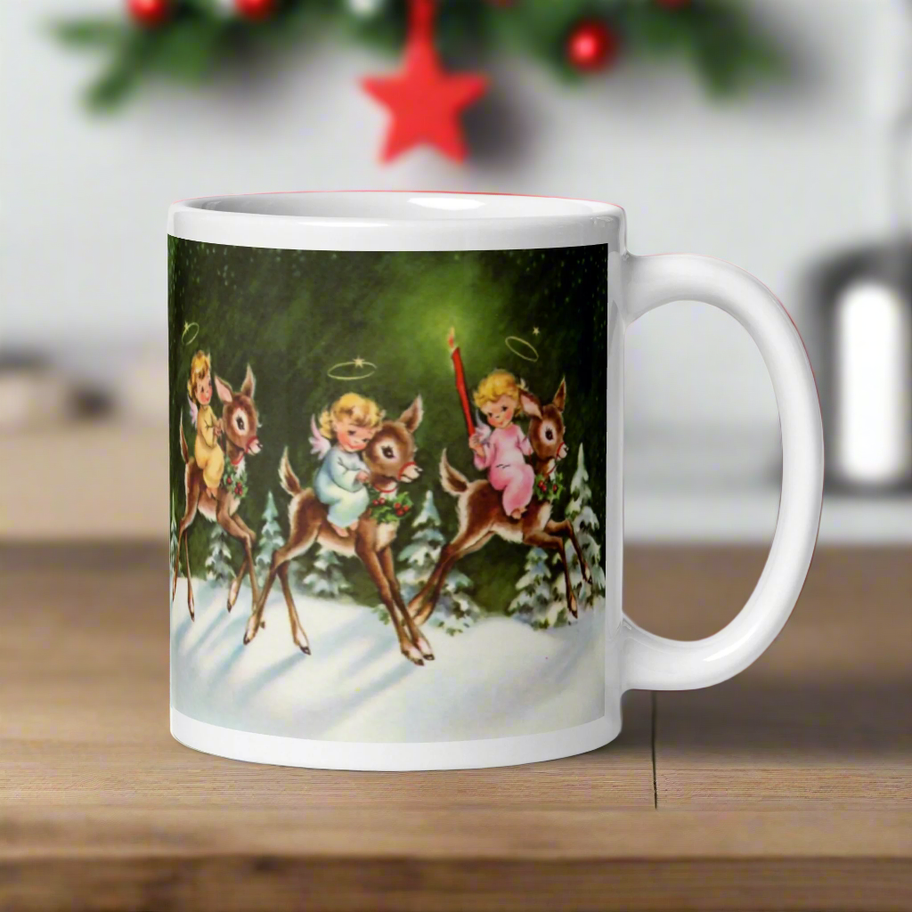 This ceramic glossy mug features three young angels riding reindeer in the snow.