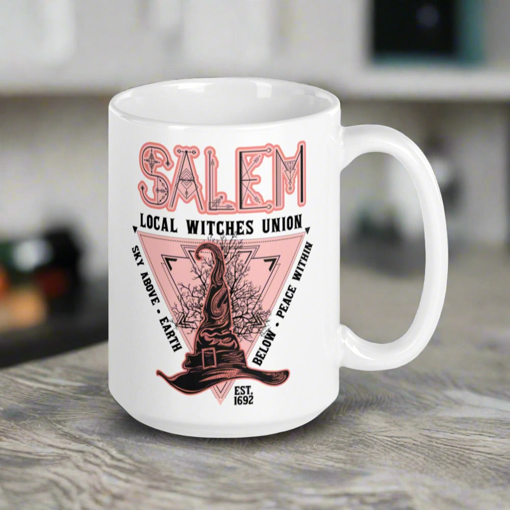 This ceramic glossy mug says Salem Local Witches Union and features a pointy pink and black witch's hat. It says Sky Above Earth Below Peace Within Est 1692.