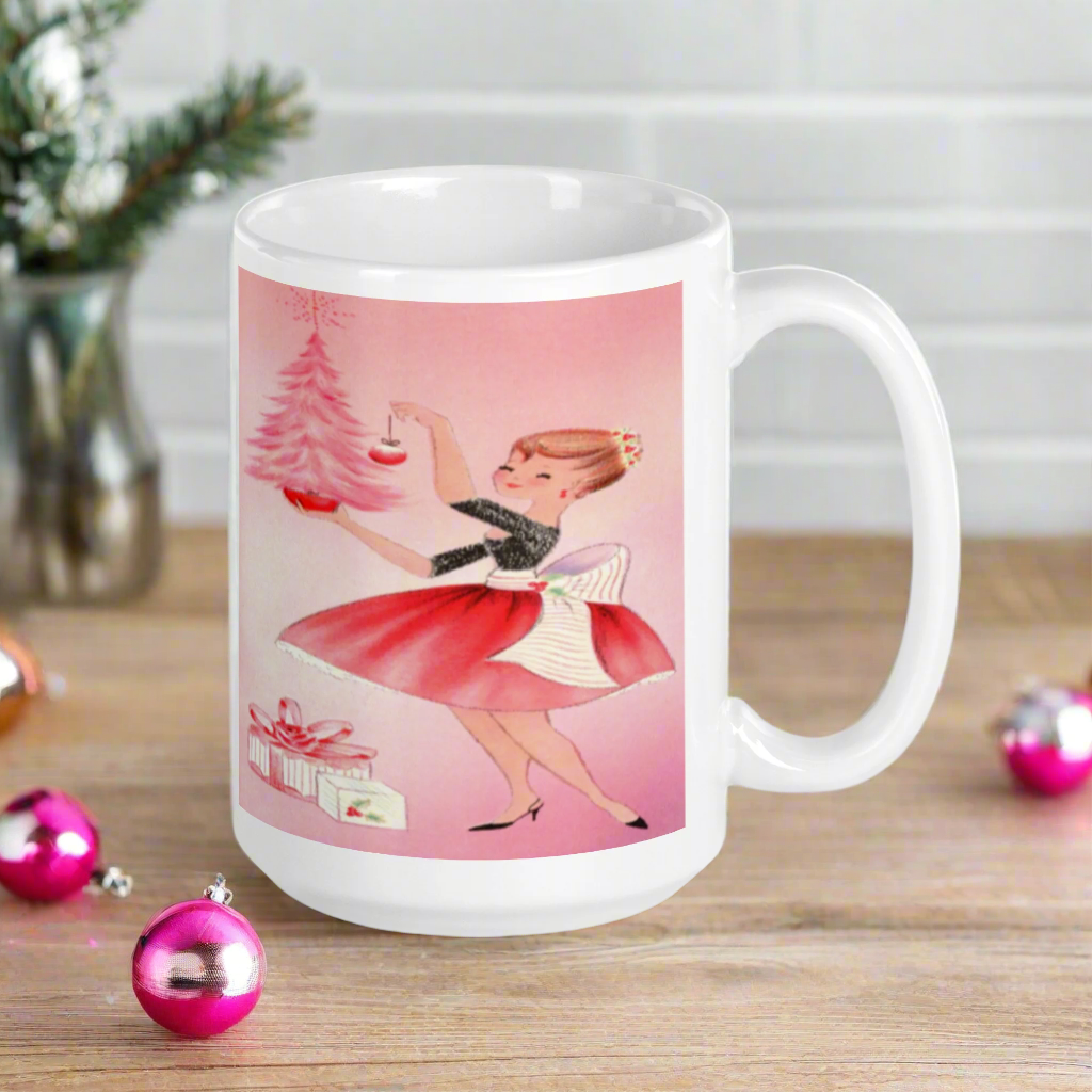 This glossy ceramic coffee mug features a midcentury retro Christmas illustration of a woman dressed in black and pink holding a small pink Christmas and ornament. There are a couple of presents and a pink background.