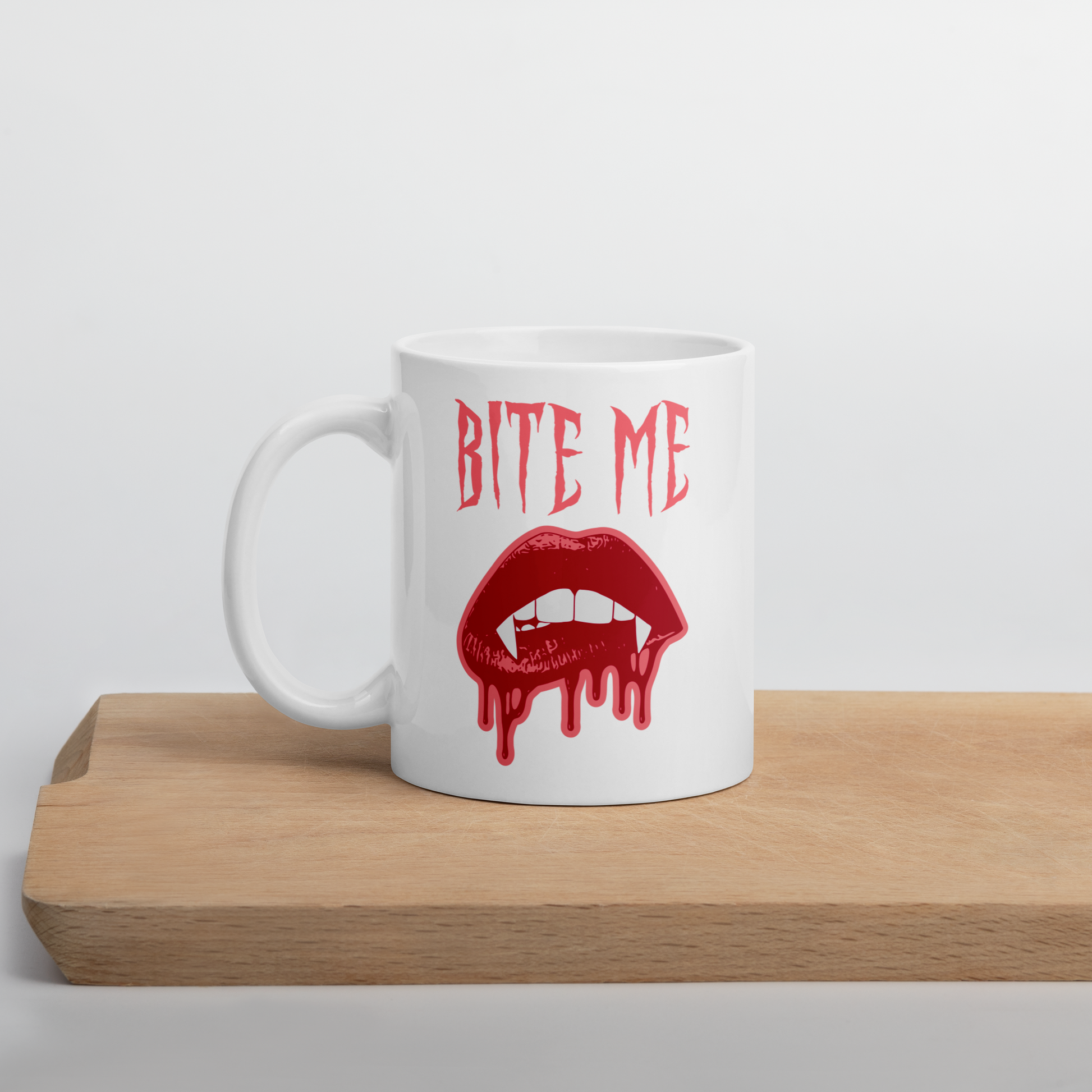 This ceramic coffee mug features the words Bite Me in gothic style with an art design of vampire lips and fangs. 