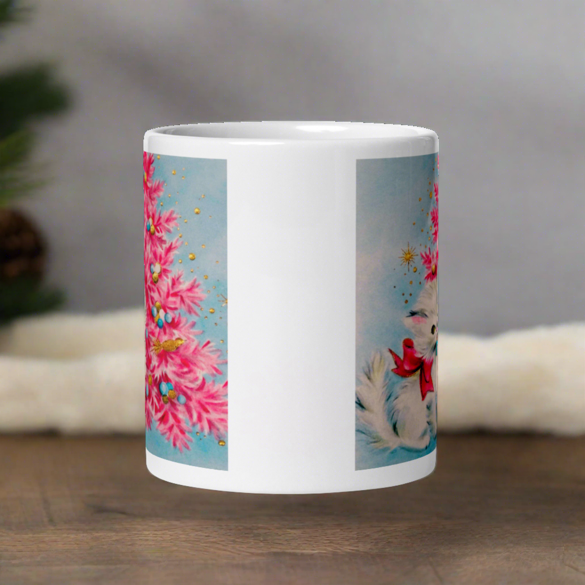 This glossy ceramic coffee cup features an adorable vintage retro print of a white christmas kitten with a blue ornament in her mouth. She is wearing a pink bow and is sitting next to a pink Christmas tree with a blue background.