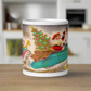 This ceramic glossy coffee mug features a midcentury Christmas illustration of Santa in a teal blue car convertible with a christmas tree in the back seat, the car is pulling his pink sleigh of presents.