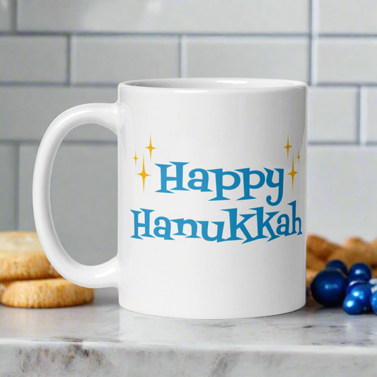 This ceramic glossy coffee mug says Happy Hanukkah in blue atomic era retro style lettering. There are golden yellow starbursts on each side of Happy.