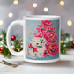 This glossy ceramic coffee cup features an adorable vintage retro print of a white christmas kitten with a blue ornament in her mouth. She is wearing a pink bow and is sitting next to a pink Christmas tree with a blue background.