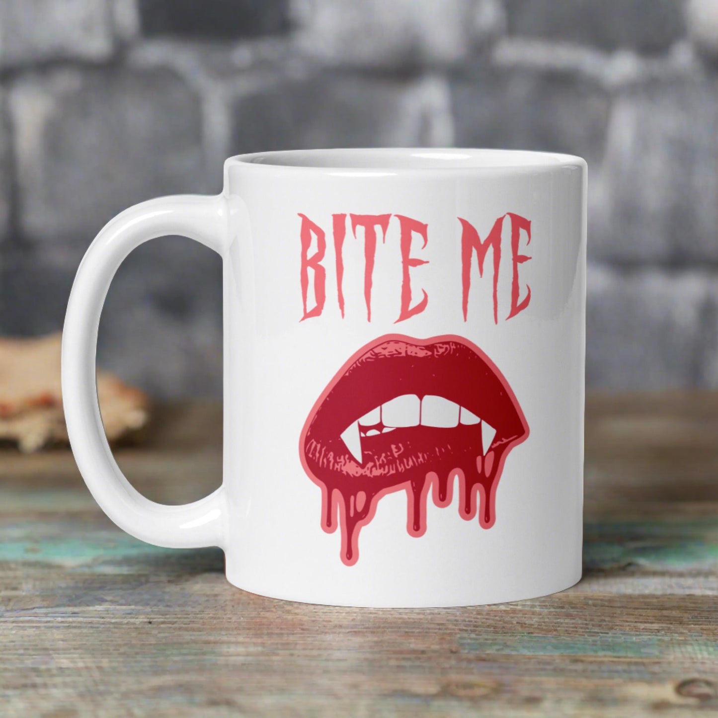 This ceramic coffee mug features the words Bite Me in gothic style with an art design of vampire lips and fangs. 