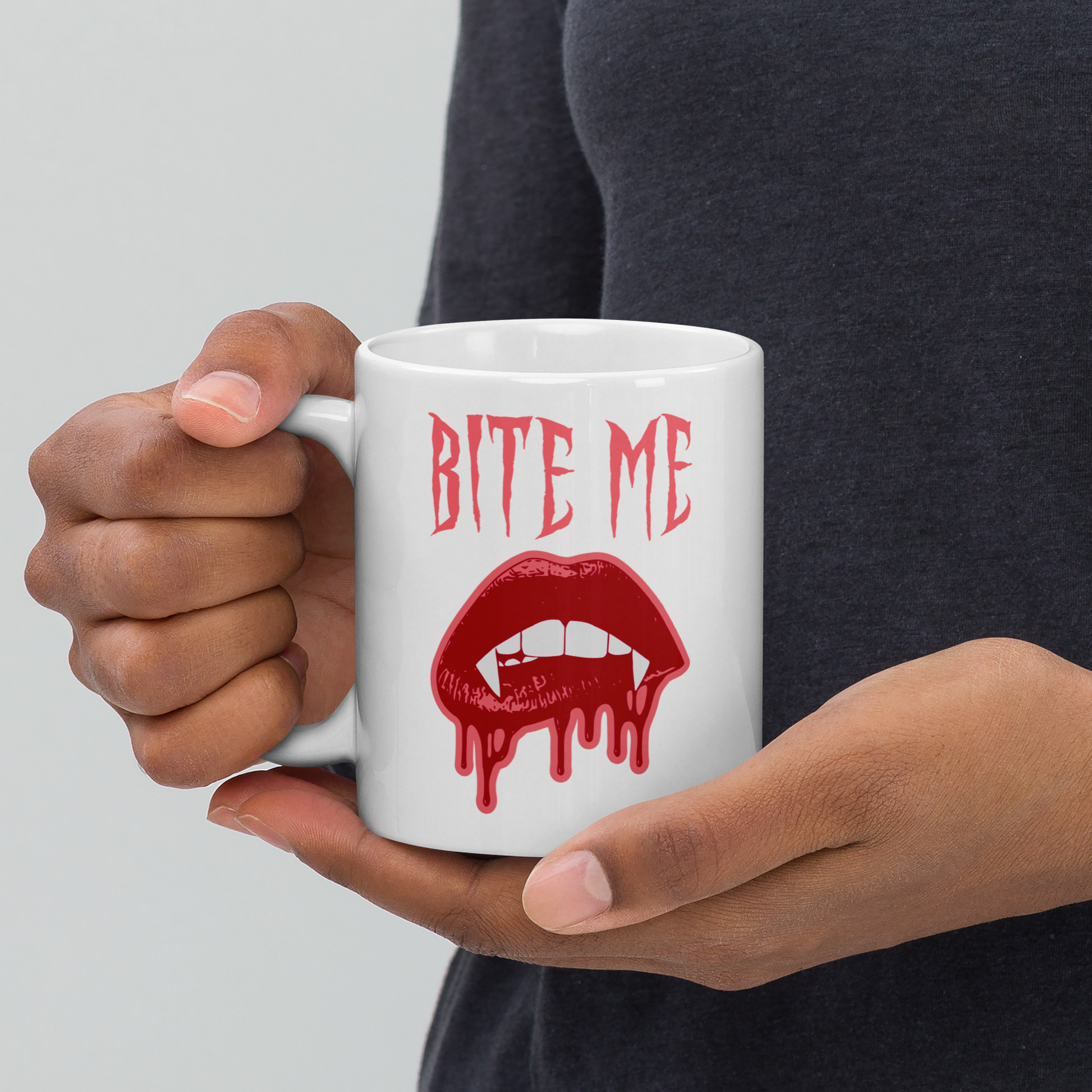 This ceramic coffee mug features the words Bite Me in gothic style with an art design of vampire lips and fangs. 