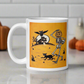 This ceramic glossy coffee mug features a vintage Halloween illustration of a skeleton with a jack o lantern for a head, a black cat, a black owl, a spooky house and a full moon. 