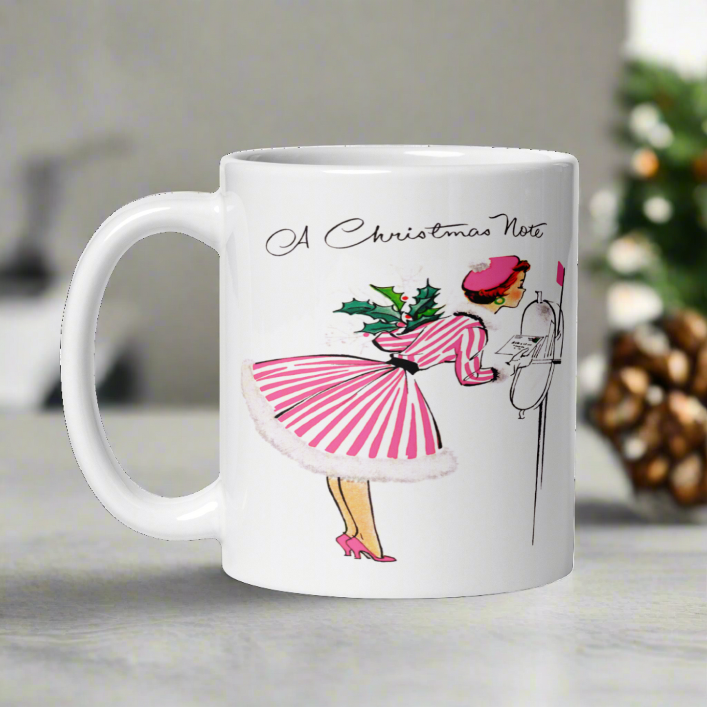 This ceramic glossy coffee mug features a retro vintage Christmas illustration of a woman holding a holly plant checking her mailbox. She is wearing a pink hat, pink and white striped dress, and pink heels. The illustration says A Christmas Note.