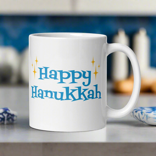 This ceramic glossy coffee mug says Happy Hanukkah in blue atomic era retro style lettering. There are golden yellow starbursts on each side of Happy.