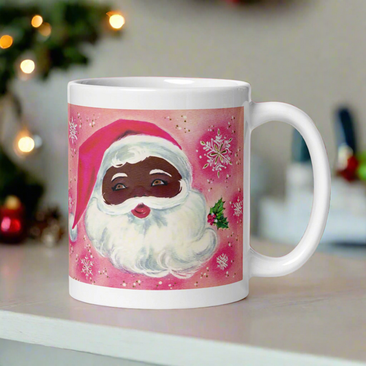 This glossy ceramic coffee mug features a retro Christmas illustration of a diverse Santa with mistletoe. There is a pink background with snowflakes.