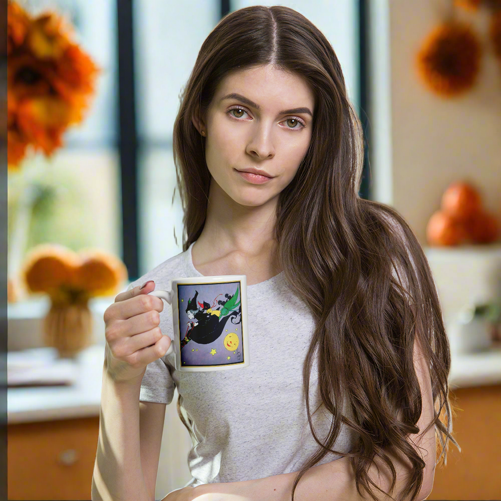 This ceramic glossy mug features a vintage Halloween illustration by Fern Bisel Peat. It features a witch dressed in all black soaring through the air on her broom with black cats. There is a smiling full yellow moon.