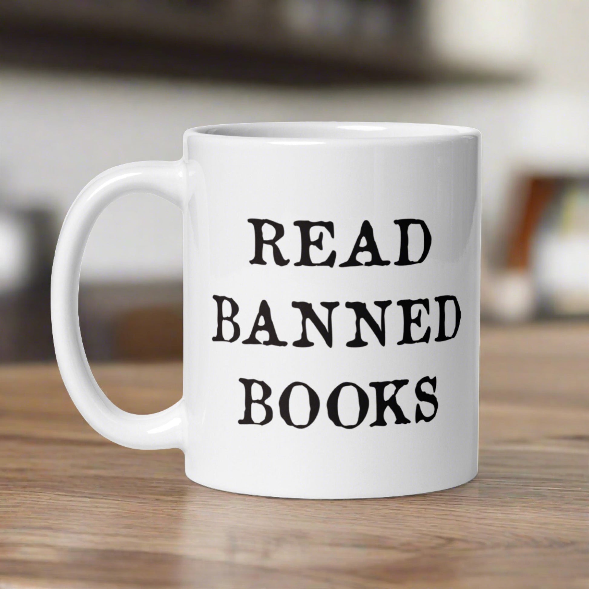 This ceramic glossy white coffee mug features black lettering that says Read Banned Books.