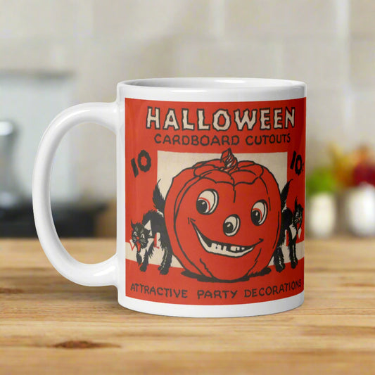 This ceramic glossy coffee mug features a retro illustration of Halloween Decorations. It says Halloween Cardboard Cutouts Attractive Party Decorations. There are two black cats and a jack o lantern.