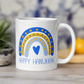 This ceramic glossy coffee cup says Happy Hanukkah and features a blue and yellow boho rainbow with a heart.