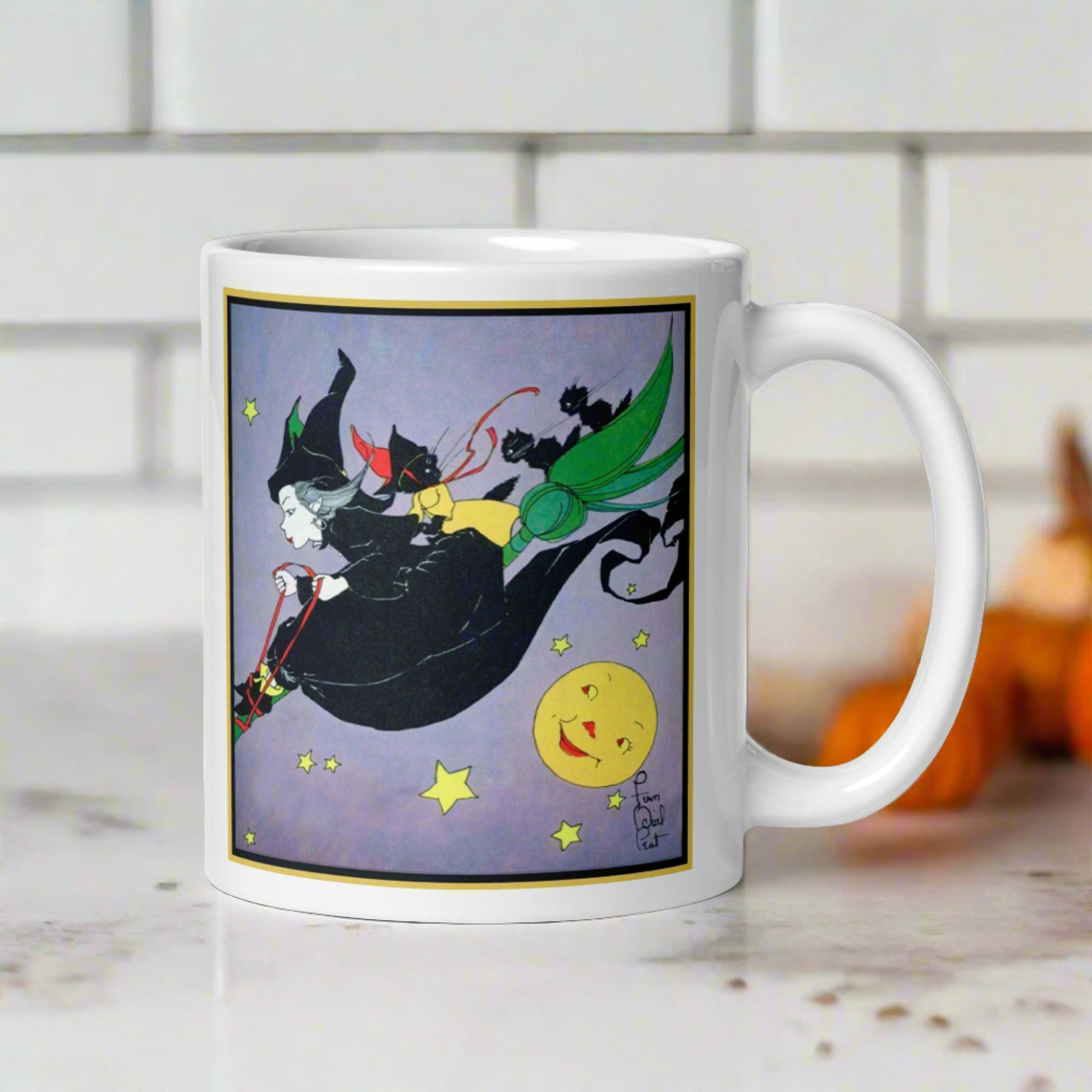 This ceramic glossy mug features a vintage Halloween illustration by Fern Bisel Peat. It features a witch dressed in all black soaring through the air on her broom with black cats. There is a smiling full yellow moon.