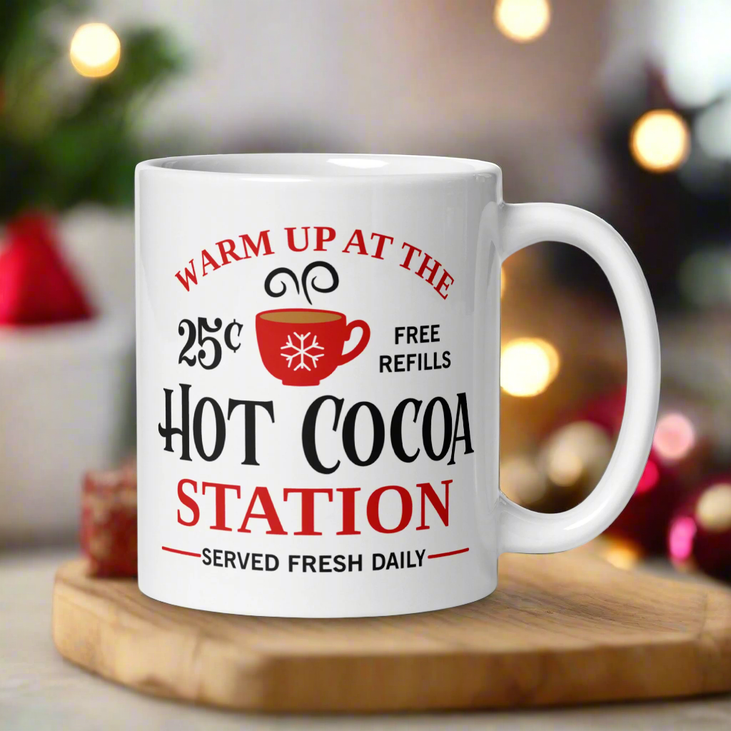 This ceramic glossy coffee mug says Warm Up At The Hot Cocoa Station Served Fresh Daily.It features a cute little red cup with a snowflake on it.