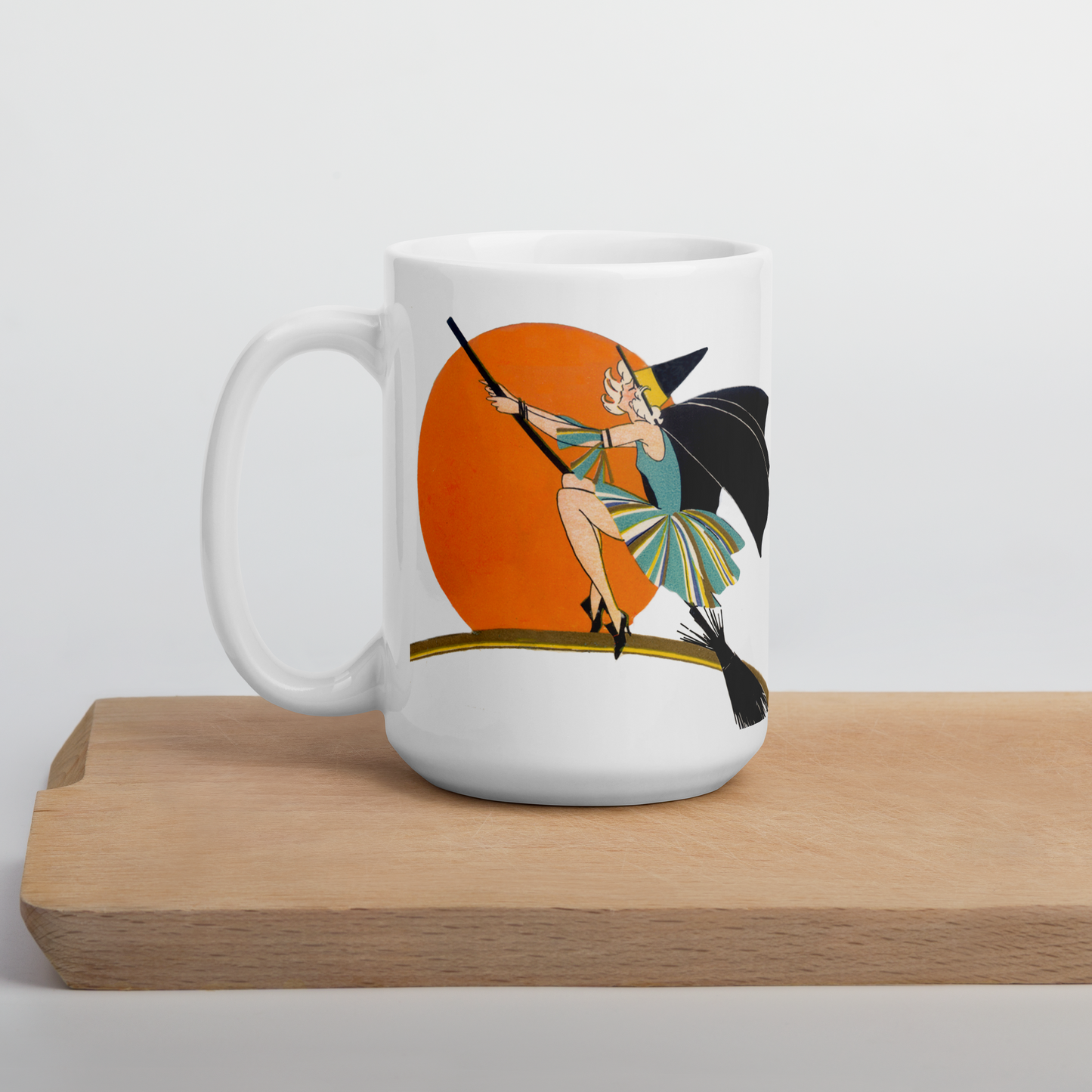 This ceramic coffee mug features a vintage deco illustration of a cute flapper witch flying on a broom with an orange full moon behind her. 