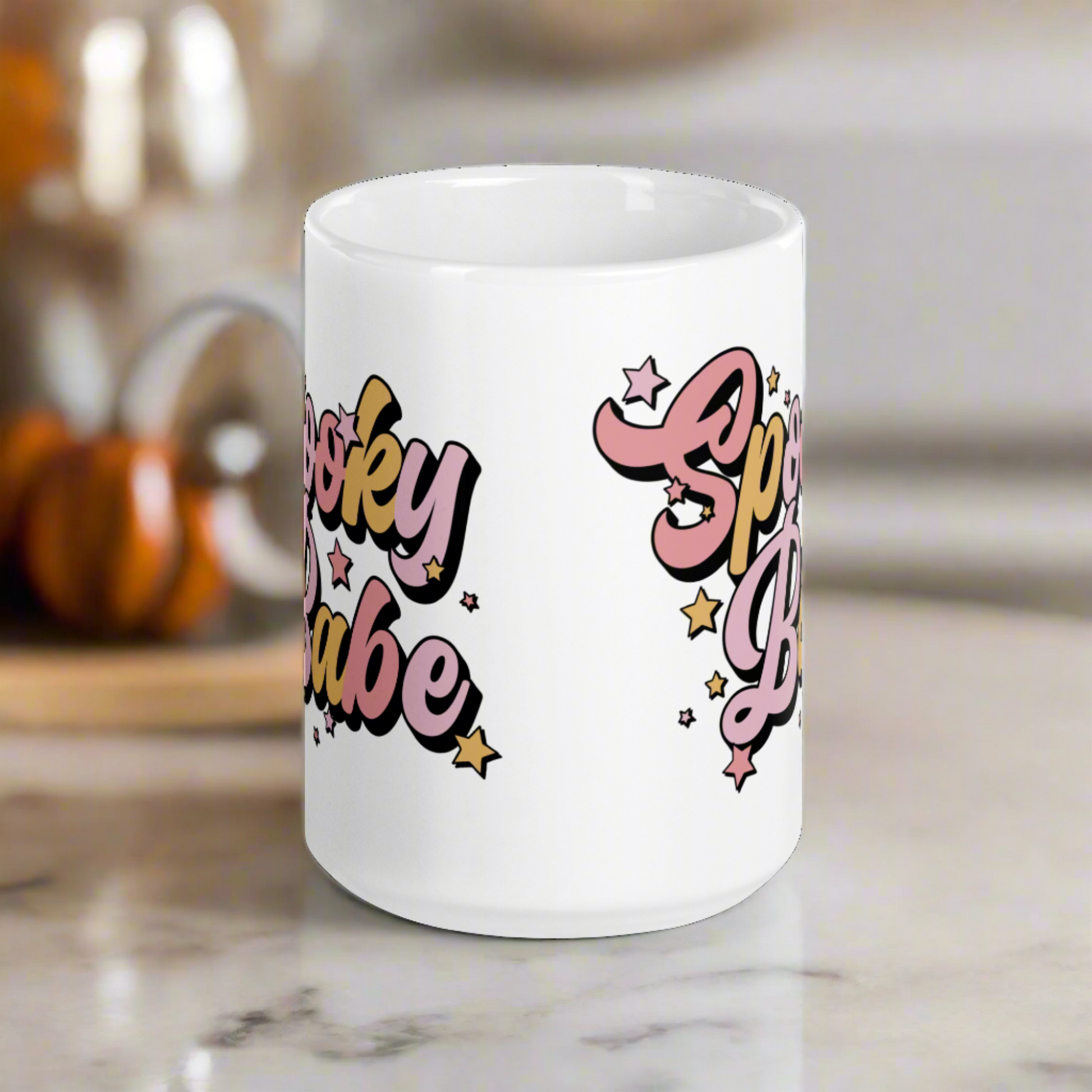 This ceramic glossy coffee mug features cursive lettering that says Spooky Babe. The colors are pastel pinks and yellows and have stars.