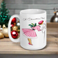 This ceramic glossy coffee mug features a retro vintage Christmas illustration of a woman holding a holly plant checking her mailbox. She is wearing a pink hat, pink and white striped dress, and pink heels. The illustration says A Christmas Note.