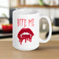 This ceramic coffee mug features the words Bite Me in gothic style with an art design of vampire lips and fangs. 