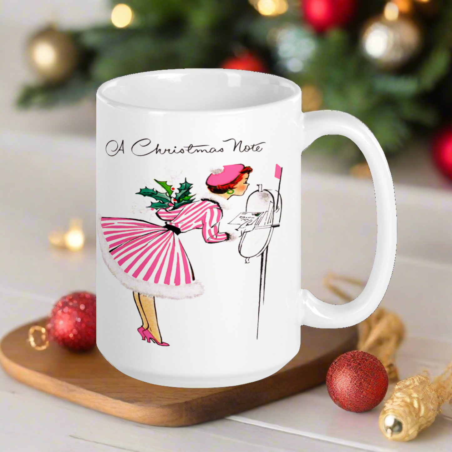 This ceramic glossy coffee mug features a retro vintage Christmas illustration of a woman holding a holly plant checking her mailbox. She is wearing a pink hat, pink and white striped dress, and pink heels. The illustration says A Christmas Note.