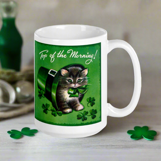 This ceramic glossy coffee mug features a midcentury retro St. Patrick's day illustration that says Top of the Morning! with a kitten sitting in a leprechaun hat surrounded by shamrocks.