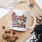 This ceramic glossy coffee mug features cursive lettering that says Spooky Babe. The colors are pastel pinks and yellows and have stars.